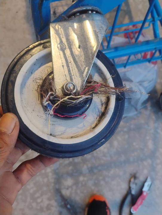 Cart caster wheel wound with hair and debris before cleaning