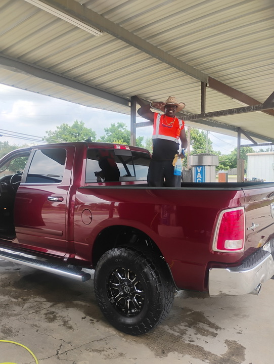Freshly washed lifted maroon pickup gleaming at a wash bay
