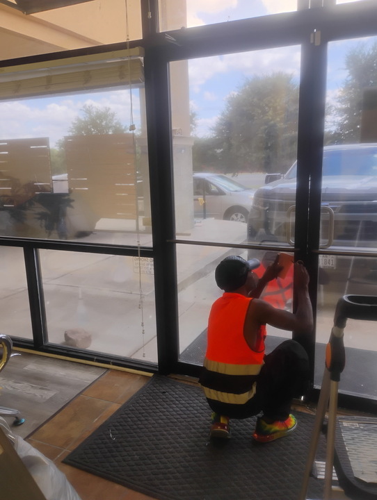 M1 applying window film to a storefront glass door